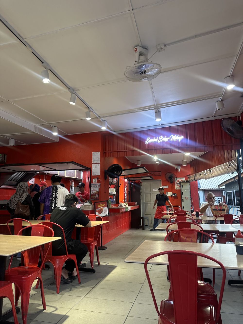 Inside the restaurant, red chairs and neon sign